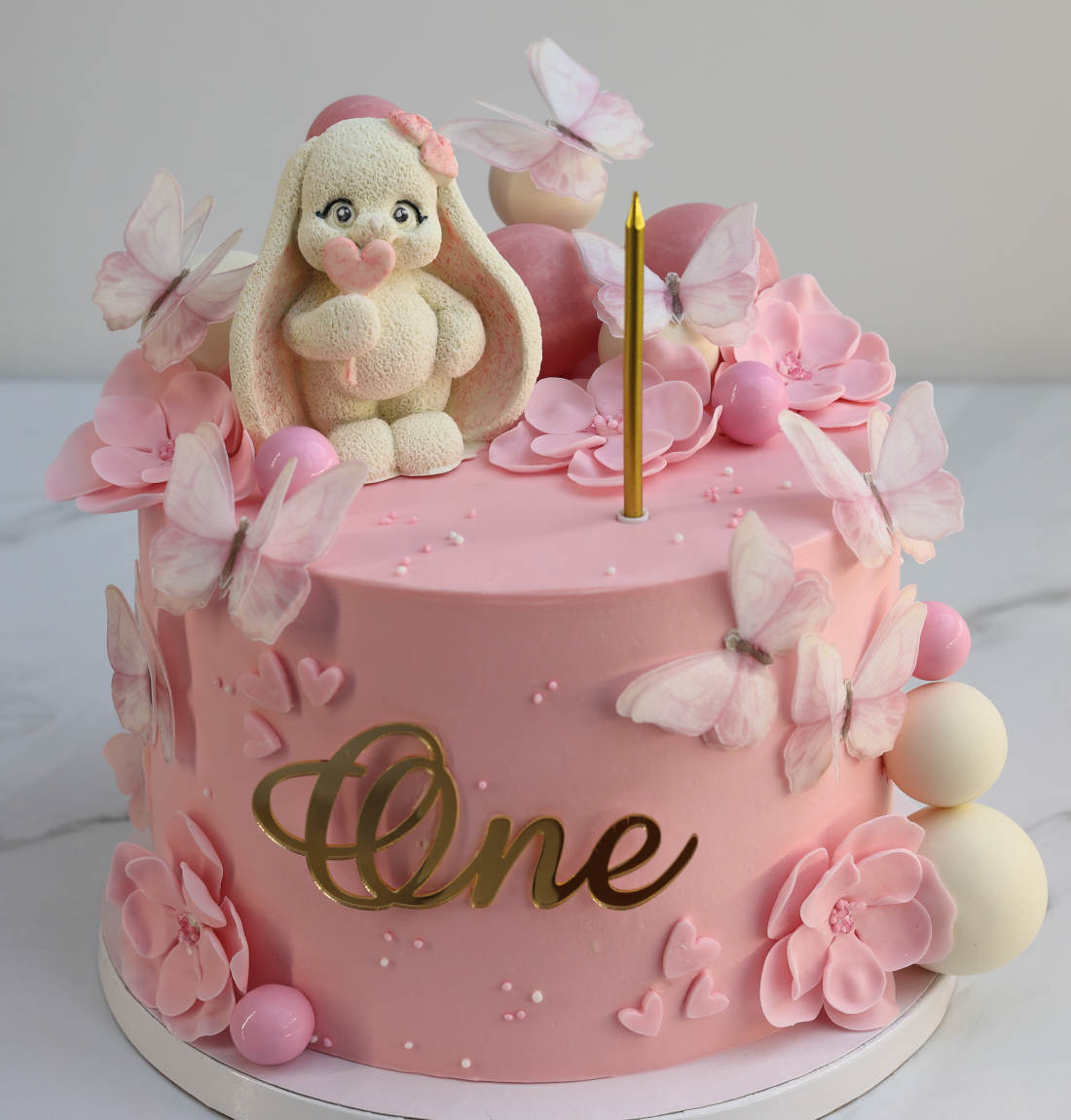 Rabbit on a pink cake with butterflies and flowers