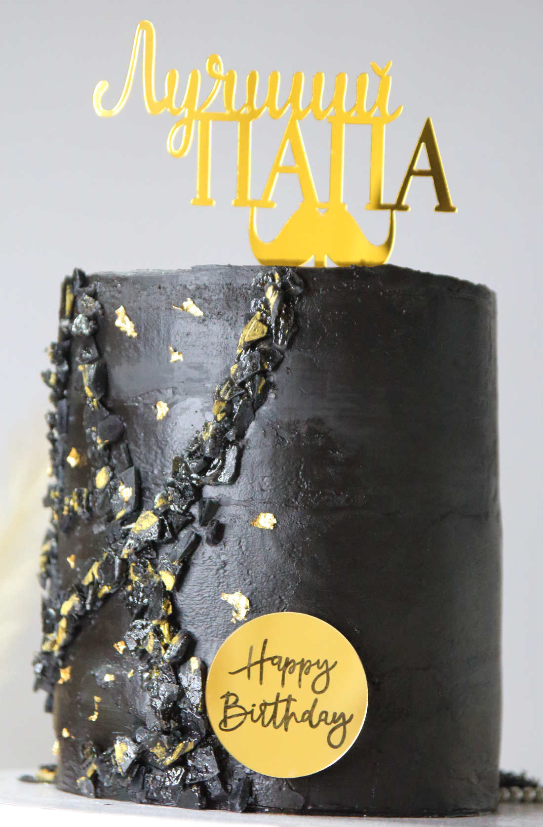 Black cake with chocolate ganache and gold foil for dad's birthday