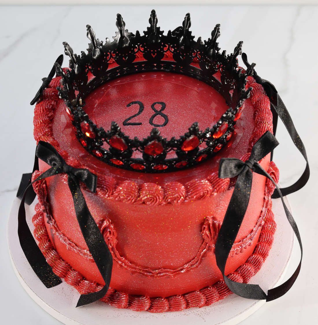 Red cake with a black crown and ribbons