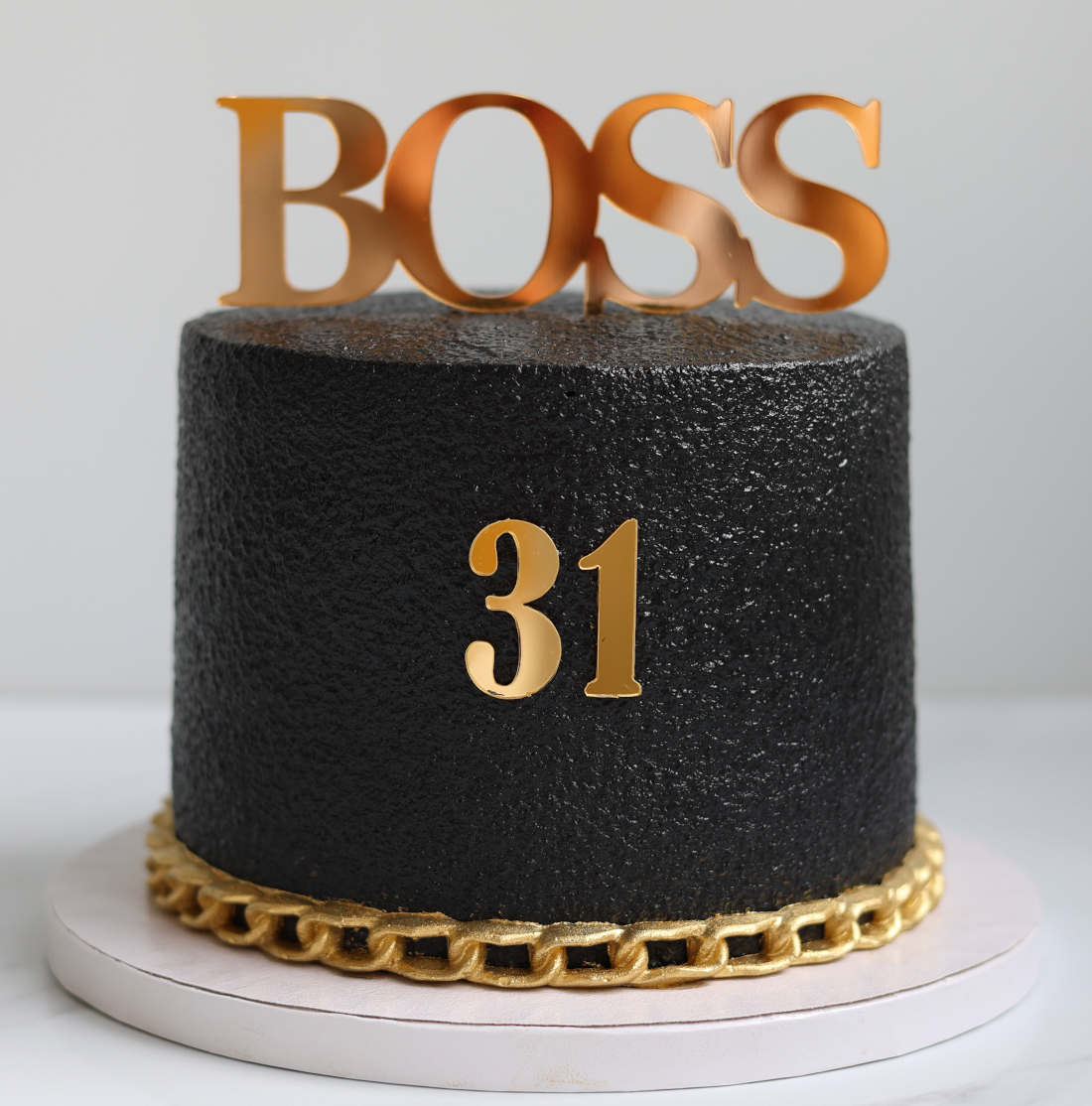 Juodas tortas su auksine grandine ir užrašu BOSS