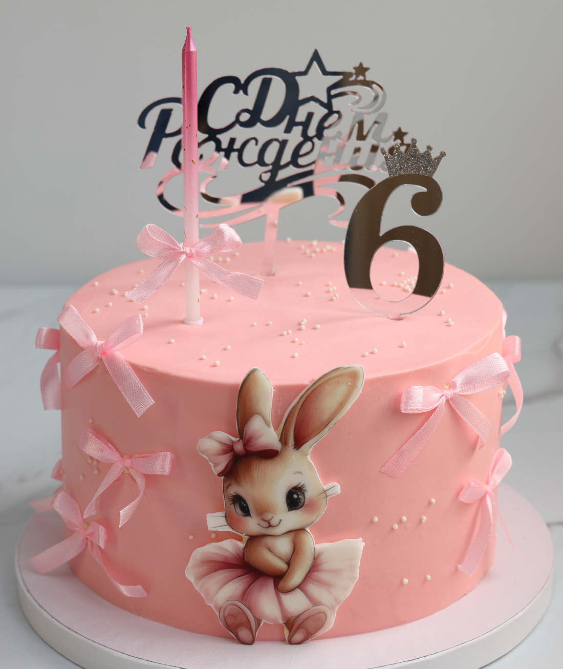 Female bunny, bows, and a candle on a birthday cake for a girl