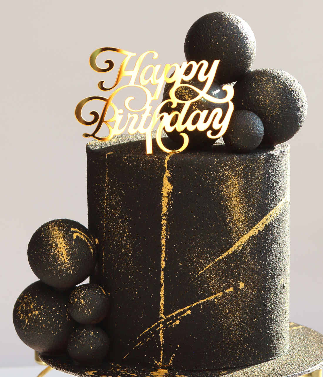 Black cake with chocolate velor, balls and gold paint