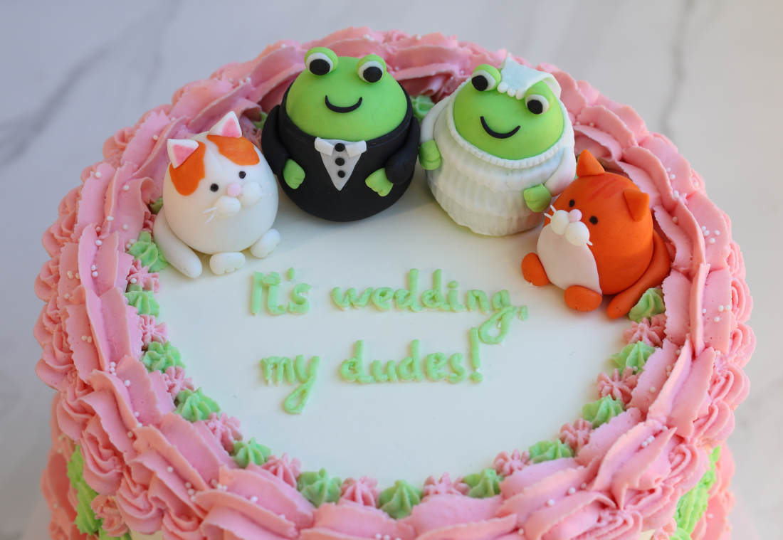 Wedding cake with an inscription and funny kittens and frogs dressed as a bride and groom