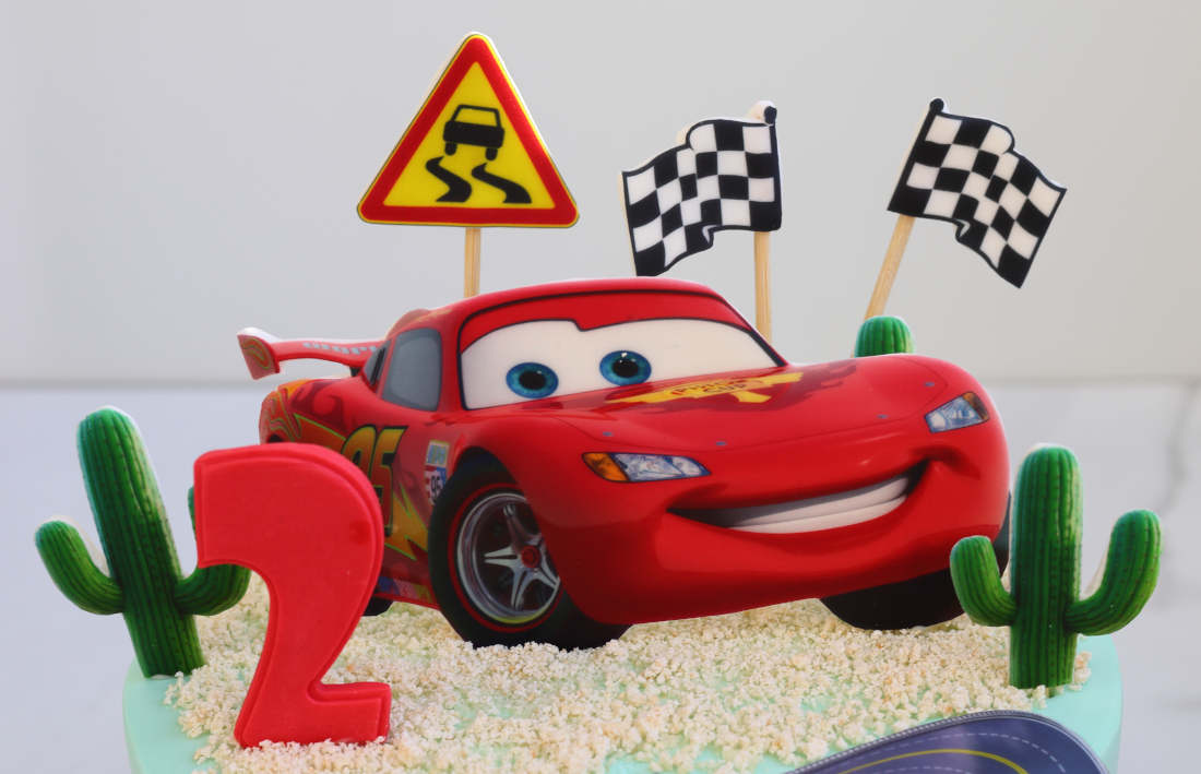 Lightning McQueen, cacti, a road sign and a finish line flags on the cake