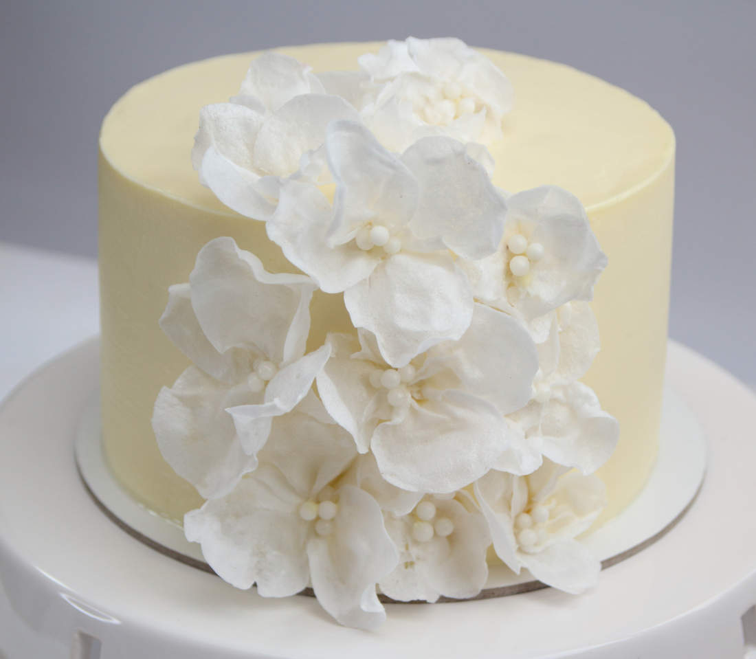 Baltas tortas su vaflinio popieriaus gėlėmis